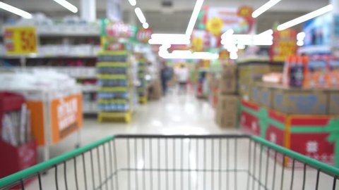 Blurred background. Shopping cart moving through supermarket
