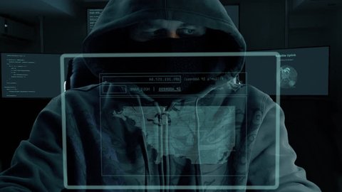 Male hacker sits in front of virtual screen in monitor room and do IP tracing via satellite uplink. Dark night low key film look.