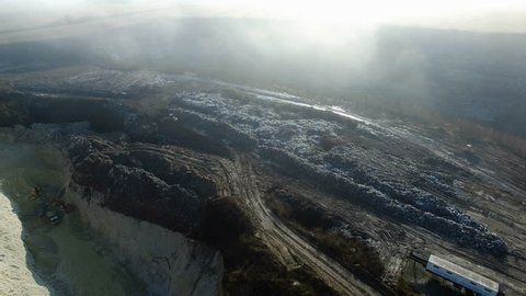 Aerial shot: fog about huge dump with working traktor 4K