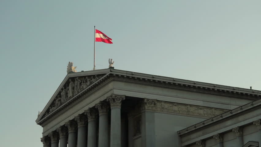 Austrian flag waving shaking in the wind on the parlament government building in the capital city Vienna