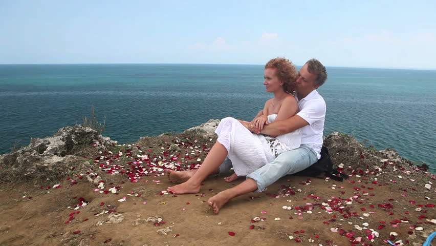 Attractive happy couple embracing each other and sitting on mountain    