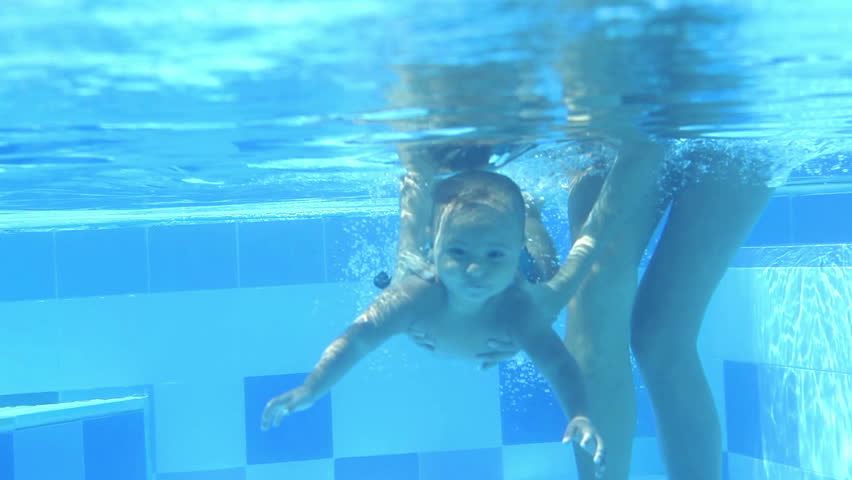 Mother holding girl swimming under water  