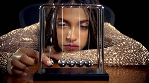 Bored woman playing with a Newton's Cradle.