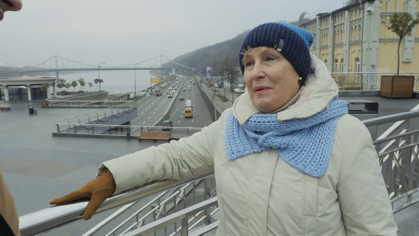 Elderly woman talks with grandson standing at the viewpoint