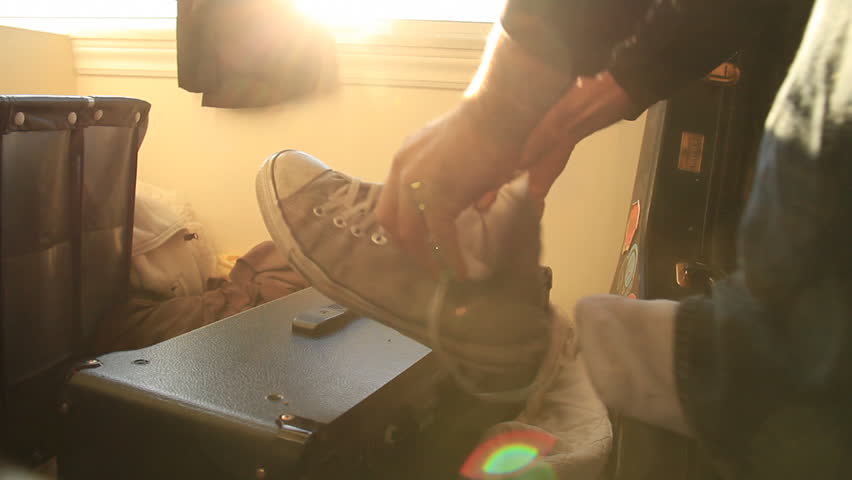 Putting on a Shoe. Putting on and tying a shoe in a messy bedroom with musical