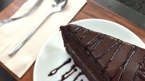 Video fork cutting delicious sweet chocolate cake on wooden table with natural light on morning