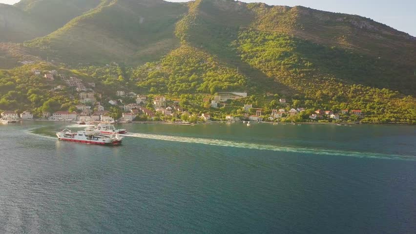 Ferryboats float between coastal towns at the shores of Kotor Bay. Aerial shot