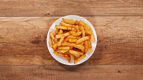 French fries escape from a central plate - leaving in every direction, top view, stop motion animation Video de stock