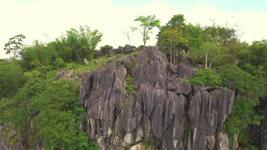 drone aerial shot of adventure touring bike rider climb to a cliff viewpoint on mountain peak