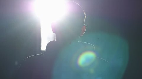 Silhouette of man standing by large window looking over the sun with lense flare effects. 3840x2160