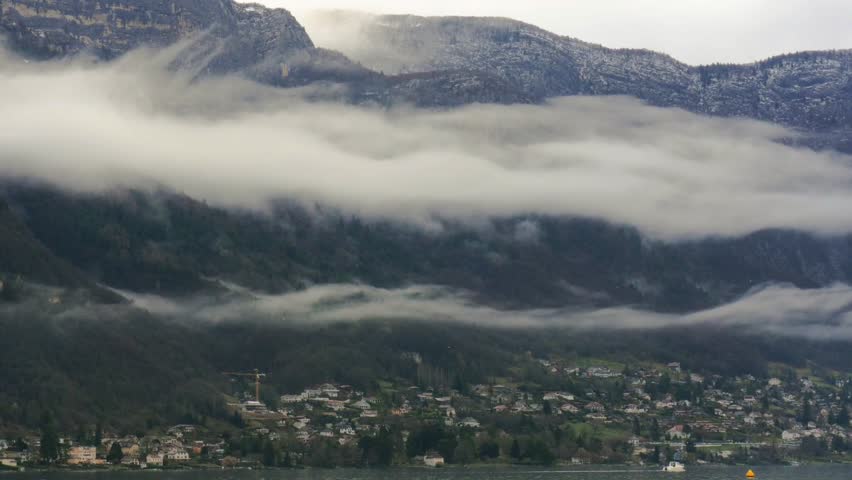 Landscape foggy clouds over city sea coast on background green hills. Panoramic view from sea low clouds above mountains in city on seashore