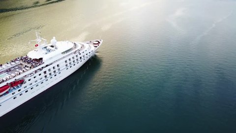 Aerial view of luxury cruise ship sailing from port on sunrise through the bay