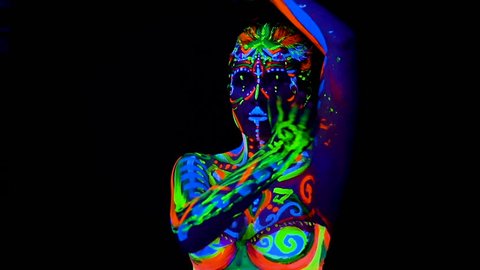 Beautiful young sexy girl in lingerie dancing with ultraviolet paint on her body. Girl with neon bodyart in color light.