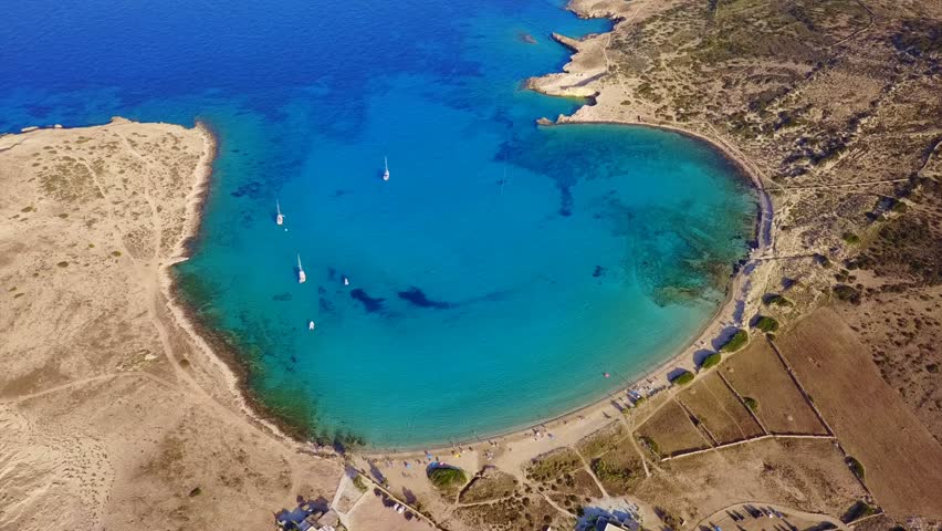 Aerial birds eye view video taken by drone depicting beautiful round beach of Pori  with deep blue - turquoise waters, Koufonisi island, Cyclades, Greece