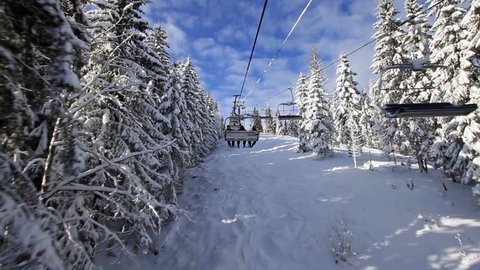 Snow forest and skiers on a ski lift pov