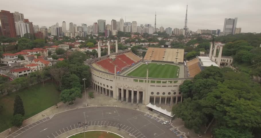 Sideways aerial of Paulo Machado de Carvalho Stadium in Sao Paulo with city skyscrapers in the background