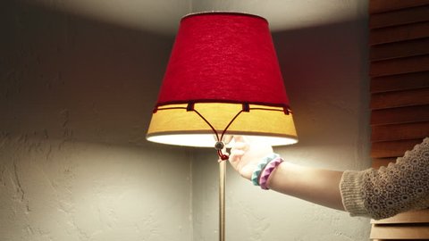 Closeup of a red and yellow lamp being turned off by a female arm