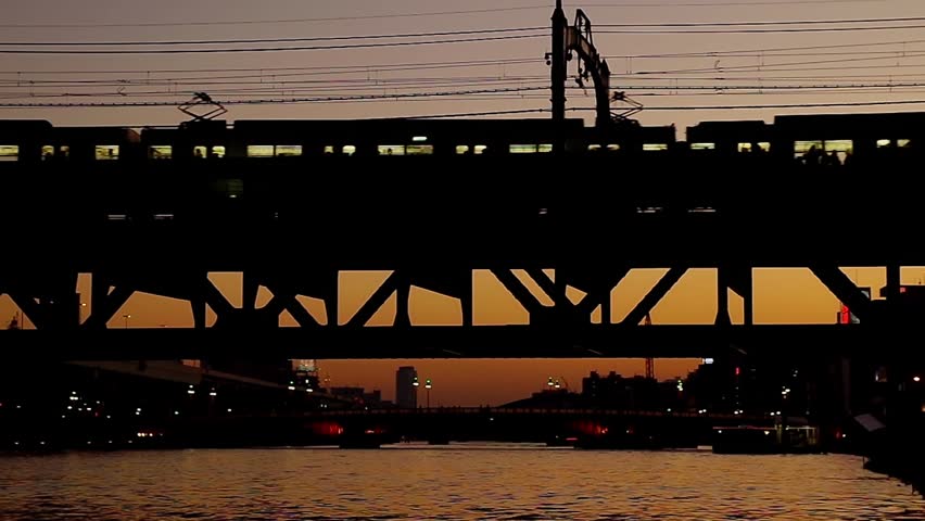 passenger train passing a bridge at dusk