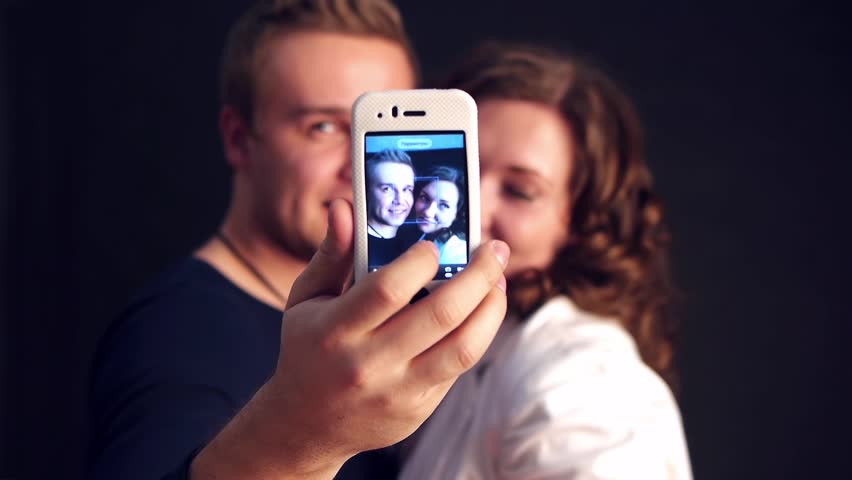 young couple making photo of themselves by a phone camera