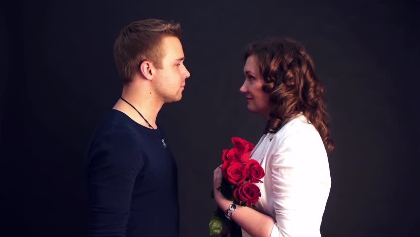 young man kissing his woman with red roses