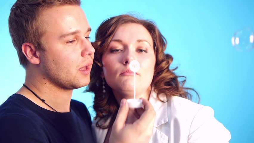 young couple blowing bubbles laughing