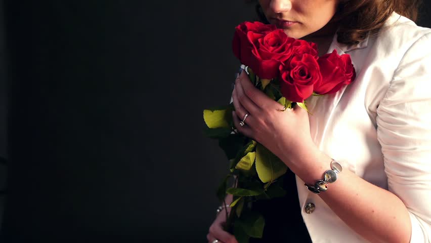 woman smelling presented red roses close-up