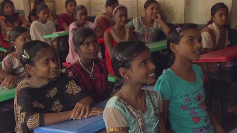 School girls sitting in a classroom are smiling and replying to a teachers questions in Chandrapur, Maharashtra, India (2017)