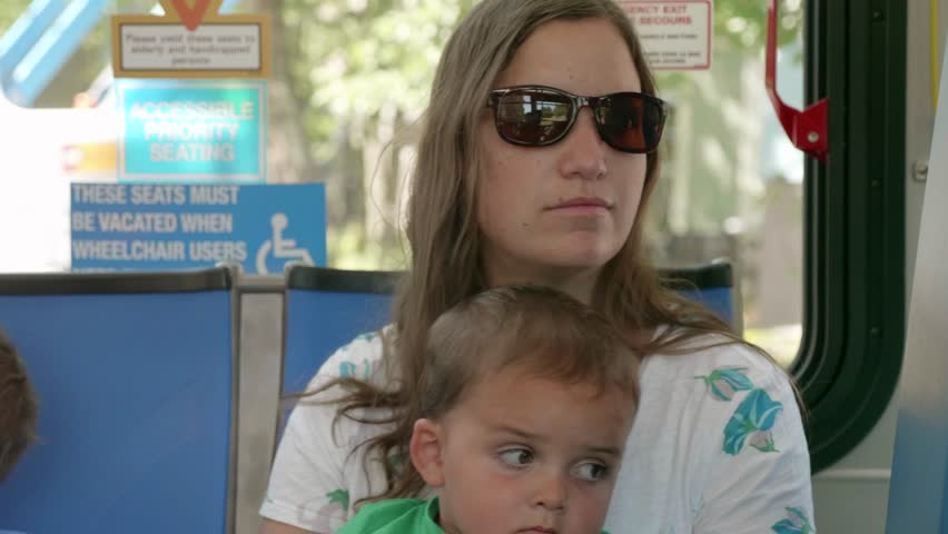 A young mother with two little boys riding on a public city bus