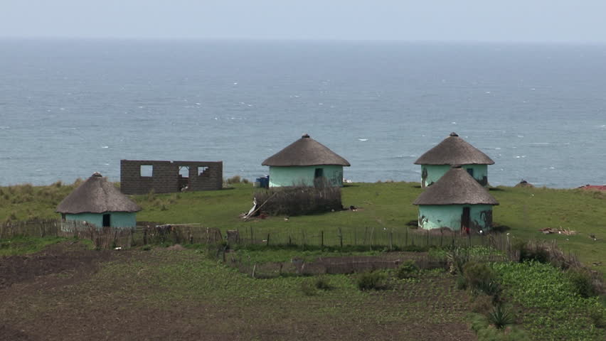 A wide shot of Xhosa huts with the sea in the background in the Transkei.