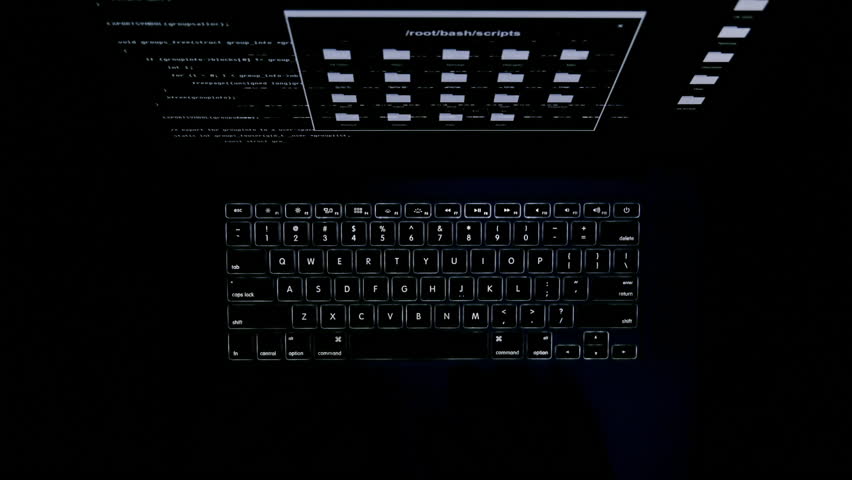 The computer keyboard glows in the dark. Keyboard backlight. The fingers are typing on the keyboard. The hacker works at night in total darkness. Computer monitor screen. Top view.