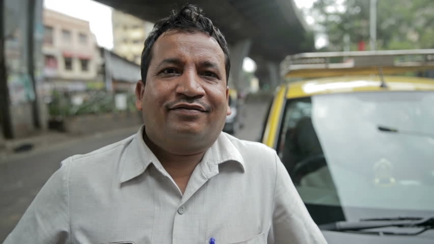 A close up and candid shot of a proud and smiling taxi driver standing in front of his taxi while vehicles passing in the background | Shutterstock HD Video #33344998