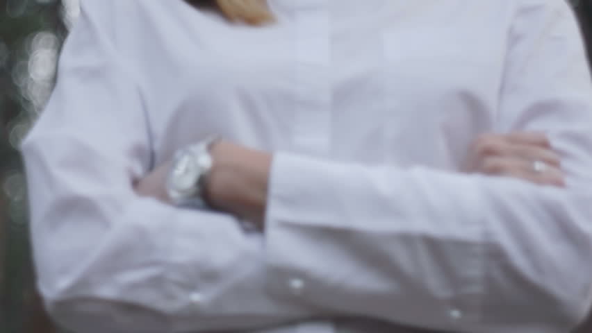 view from below on a young woman with arms crossed on her chest. girl in a white shirt in the woods