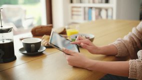 Cropped video of woman using digital tablet at breakfast table