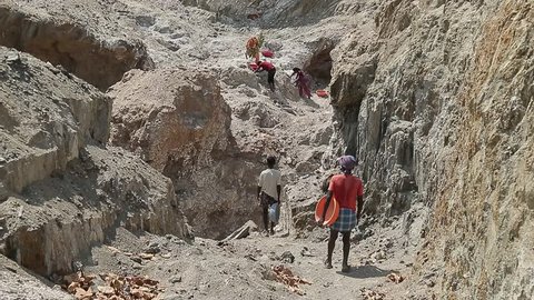 Employment and manual labor in India, poor unrecognizable Indian mine worker with empty basins. Mining minerals in third world countries.
