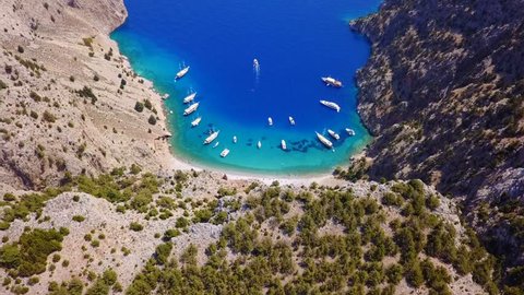 Aerial birds eye view video taken by drone of famous tropical rocky beach of Agios Georgios with yachts docked, Symi island, Dodecanese, Greece