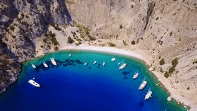 Aerial birds eye view video taken by drone of famous tropical rocky beach of Agios Georgios with yachts docked, Symi island, Dodecanese, Greece