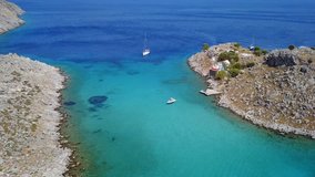 Aerial birds eye view video taken by drone of tropical rocky island with yachts docked and turquoise clear waters