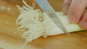 Closeup Of Man Cutting Spring Onion On Chopping Board