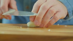 Man's Hands Sprinkling Salt And Chopping Garlic On Cutting Board
