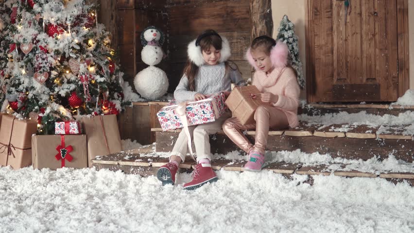 Christmas or New Year. children are looking at presents in beautiful Christmas boxes. two little girls on a christmas tree background
