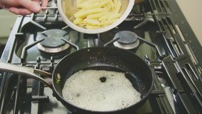 Man Pouring Boiled Pasta In Skillet On Stove