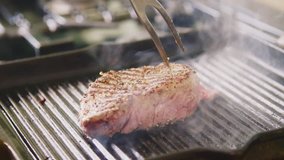 Man Flipping Grilled Fillet Steak With Fork In Kitchen