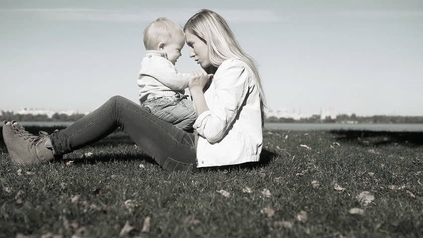 Baby has fun with mother on the grass in park