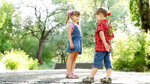 Two child speaking and boy present flower