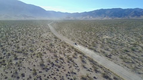 Truck driving on dusty desert road in bright sunshine, distant follow into sun.  Filmed outside Lime Kiln Canyon in North West Arizona near Mesquite, Nevada.