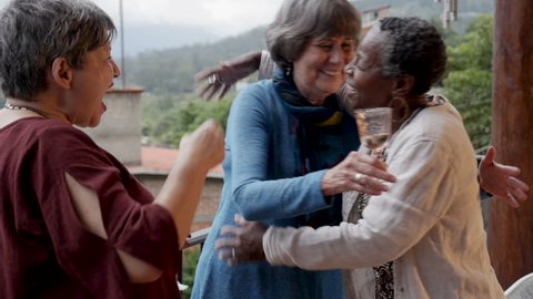 Beautiful African American senior woman in her 60s hugging her friends at a small party overlooking a spectacular mountain view in slow motion