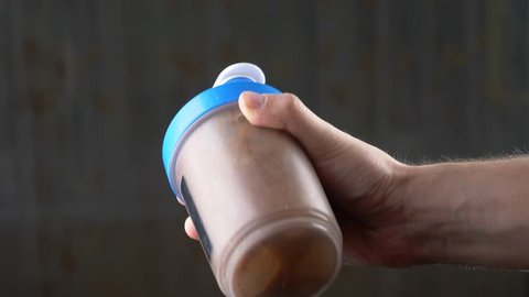 Slow motion. 4k. Young man making a protein shake at home. anonymously