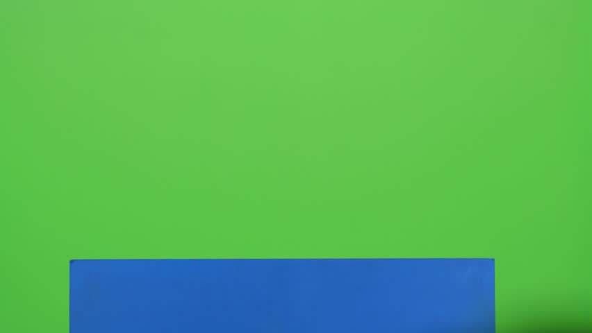 Child boy appeared from behind a blue poster to look at him shakes her head and hides again. Green screen
