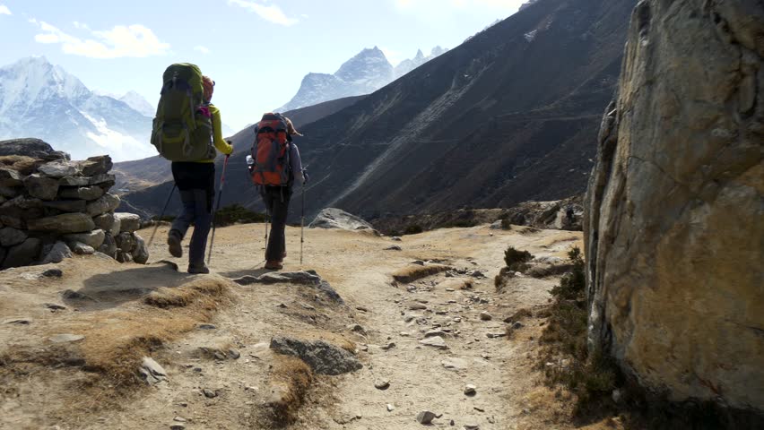 Hiking in Himalaya mountains.  Two young women with backpacks trekking on himalaya mountain trail. Everest base camp trek. Sagarmatha national park, Nepal. Steadicam shot. UHD, 4K