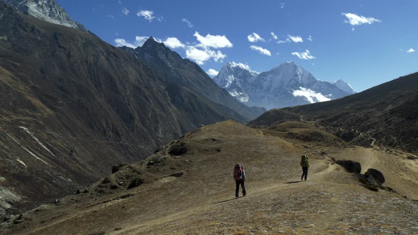 Two women backpacker trekking on himalaya mountain trail. Sagarmatha national park, EBC, Nepal. View to snowy mountains. 4K, UHD